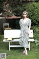 A woman standing next to a white bench in a park.